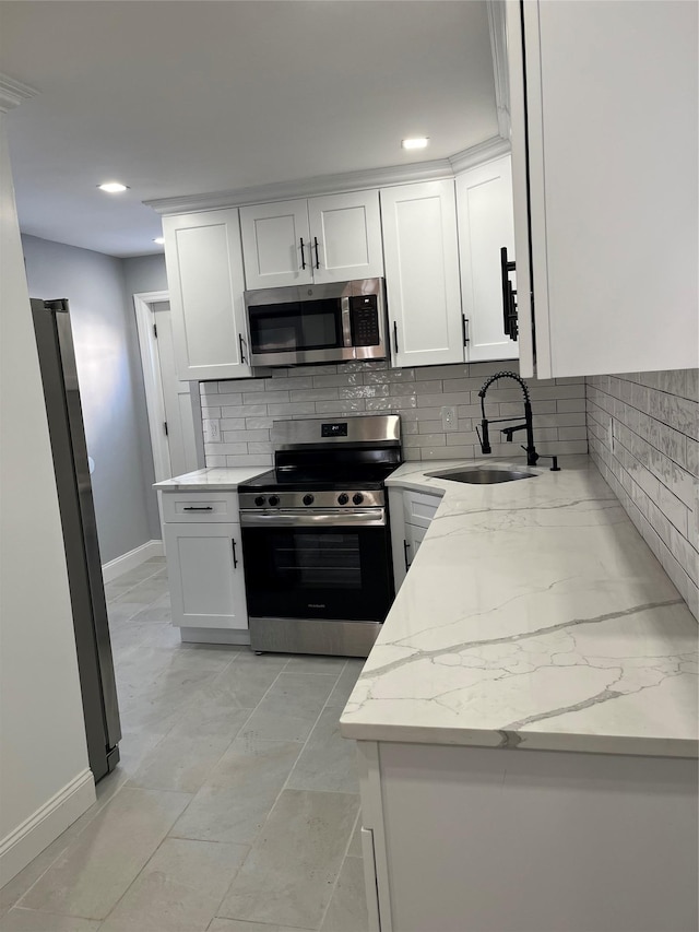 kitchen with sink, appliances with stainless steel finishes, backsplash, light stone counters, and white cabinets