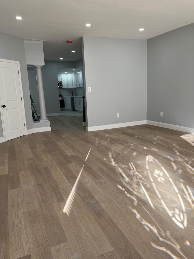 spare room with decorative columns and wood-type flooring