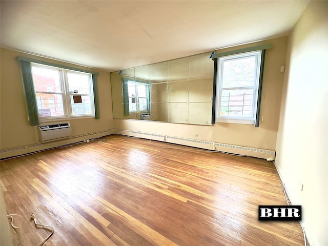 spare room featuring hardwood / wood-style floors, a wall mounted AC, and a baseboard radiator