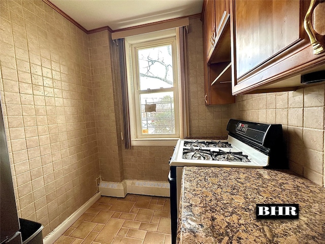 kitchen with baseboards, gas range, a baseboard radiator, crown molding, and brown cabinets