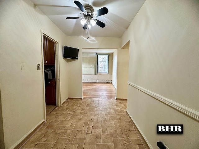 corridor with brick floor, a baseboard heating unit, and baseboards