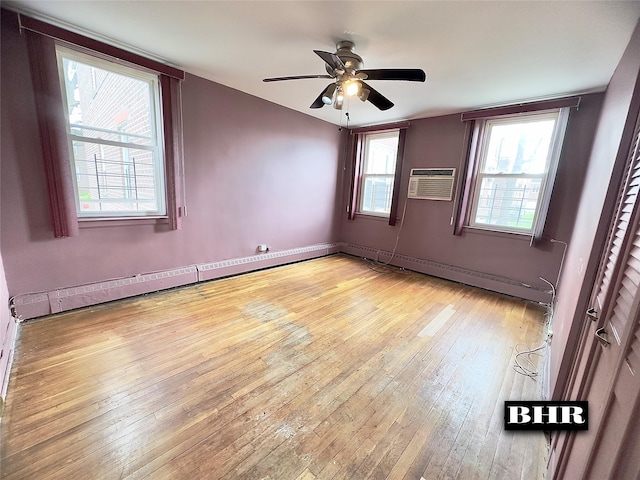 spare room featuring baseboard heating, light wood-type flooring, a wall mounted air conditioner, and a ceiling fan