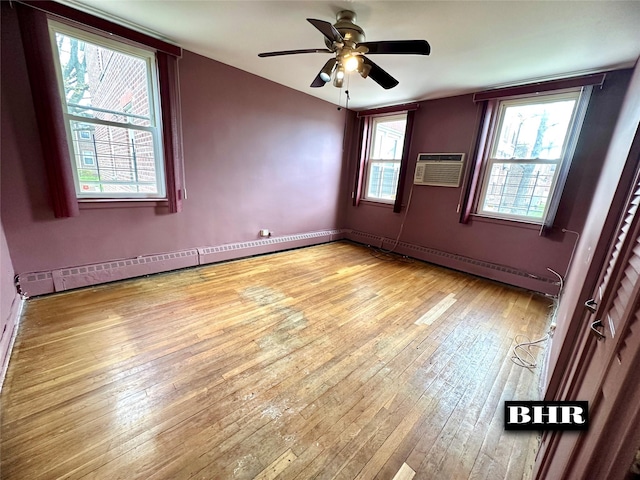 unfurnished room with light wood-style flooring, a wall mounted air conditioner, a baseboard heating unit, and a ceiling fan
