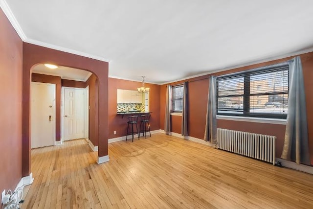 interior space featuring an inviting chandelier, ornamental molding, radiator, and light wood-type flooring