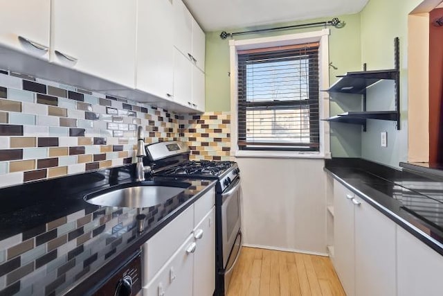 kitchen featuring white cabinets, sink, light hardwood / wood-style flooring, and stainless steel gas range oven