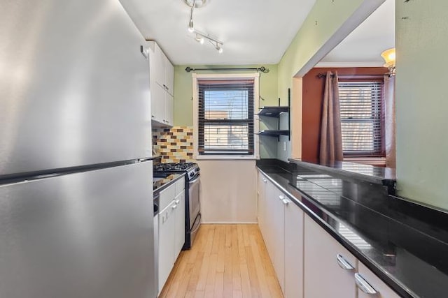 kitchen featuring appliances with stainless steel finishes, white cabinets, decorative backsplash, crown molding, and light wood-type flooring