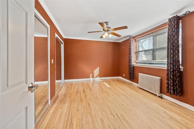 unfurnished bedroom featuring crown molding, light wood-type flooring, radiator heating unit, a closet, and ceiling fan