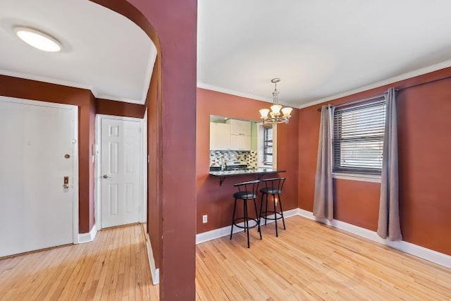 dining space featuring crown molding, a notable chandelier, and light wood-type flooring