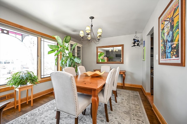 dining area with dark wood-type flooring and a chandelier