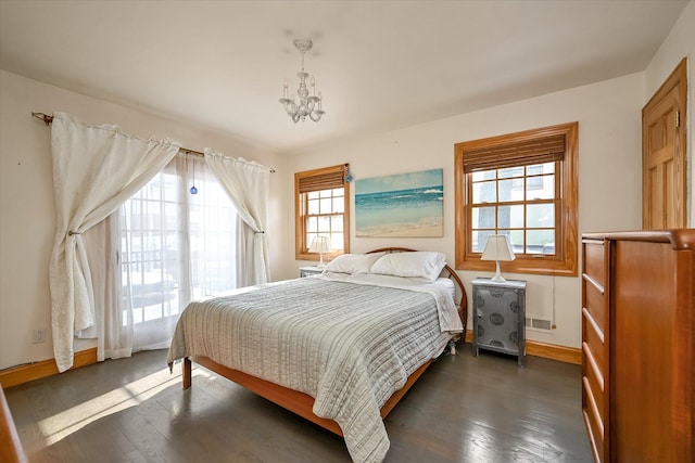 bedroom featuring a notable chandelier and dark wood-type flooring