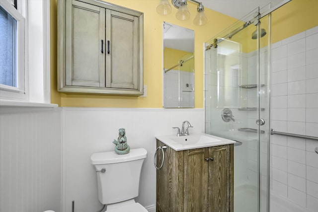 bathroom featuring a shower with door, vanity, and toilet