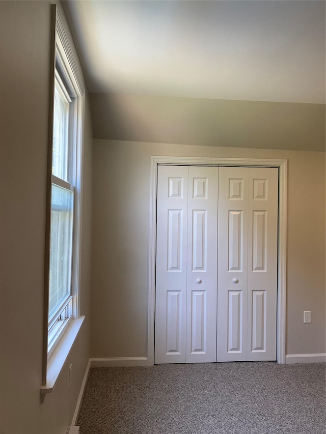 unfurnished bedroom featuring multiple windows, carpet, and a closet