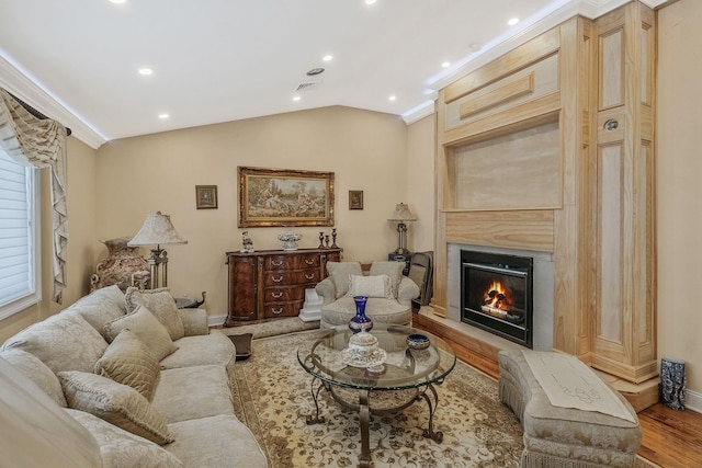 living room featuring vaulted ceiling, ornamental molding, and light wood-type flooring