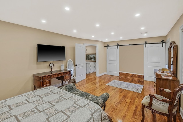 bedroom featuring a barn door and light hardwood / wood-style floors