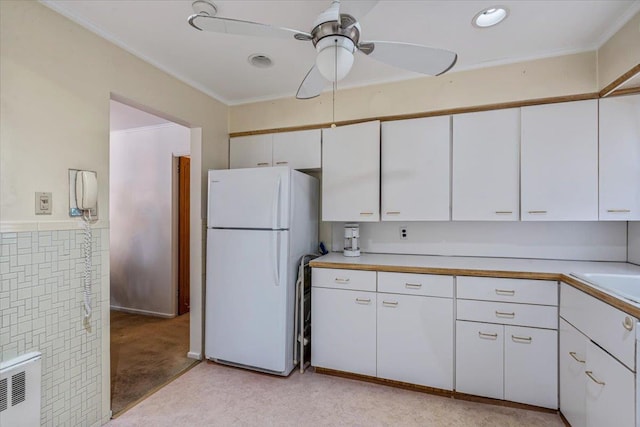 kitchen with white cabinetry, radiator heating unit, light colored carpet, and white fridge