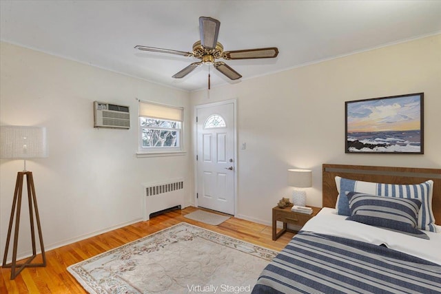 bedroom featuring an AC wall unit, radiator, ceiling fan, crown molding, and light hardwood / wood-style flooring