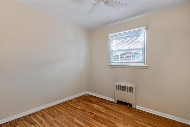 spare room with ceiling fan, ornamental molding, radiator, and hardwood / wood-style floors