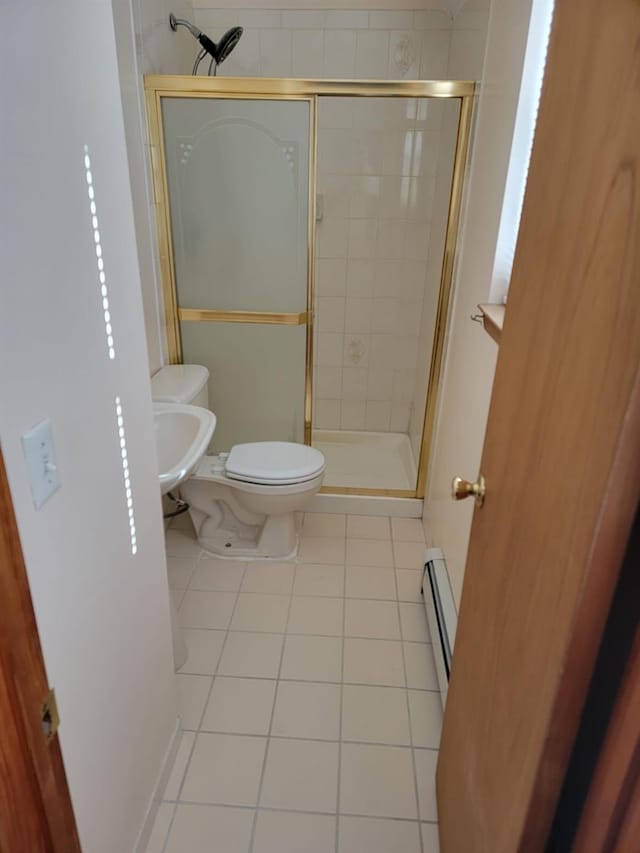 bathroom with tile patterned flooring, a baseboard radiator, a shower with door, and toilet