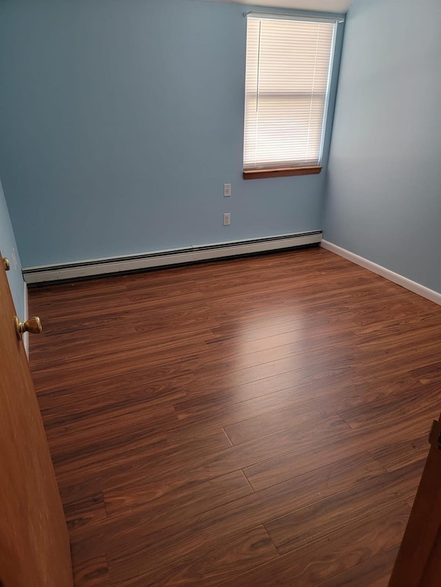 empty room with baseboard heating and dark wood-type flooring