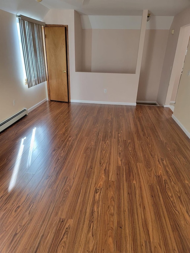 empty room featuring baseboard heating and wood-type flooring