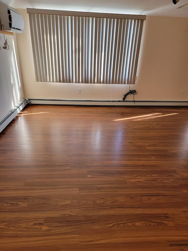 empty room with an AC wall unit, a baseboard heating unit, and hardwood / wood-style floors