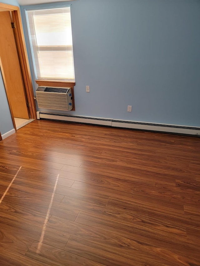 spare room featuring an AC wall unit and dark hardwood / wood-style floors