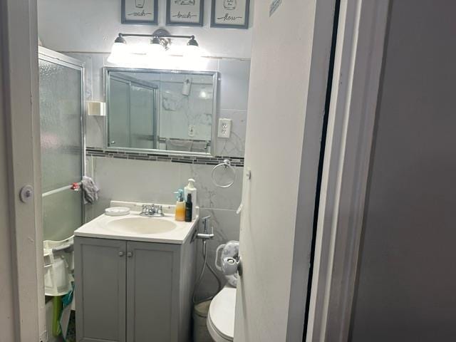 bathroom with vanity, a shower with shower door, and toilet