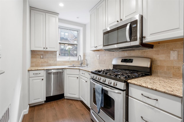 kitchen with sink, light hardwood / wood-style flooring, appliances with stainless steel finishes, light stone counters, and white cabinets