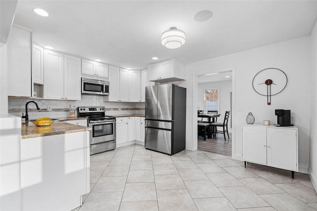 kitchen featuring tasteful backsplash, sink, white cabinets, stainless steel appliances, and light stone countertops