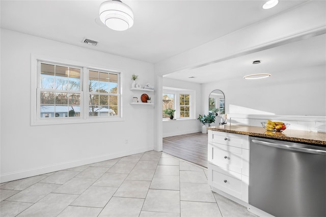 kitchen featuring white cabinetry, dishwasher, light tile patterned flooring, and dark stone counters