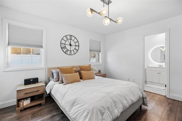 bedroom featuring connected bathroom, sink, dark hardwood / wood-style floors, and a chandelier