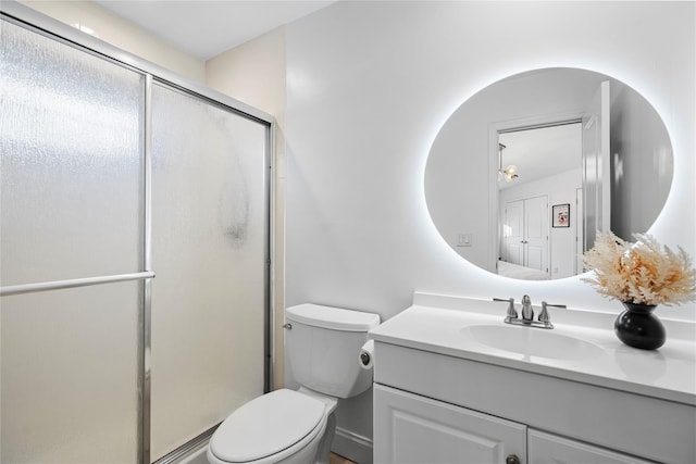 bathroom featuring vanity, toilet, and a shower with door