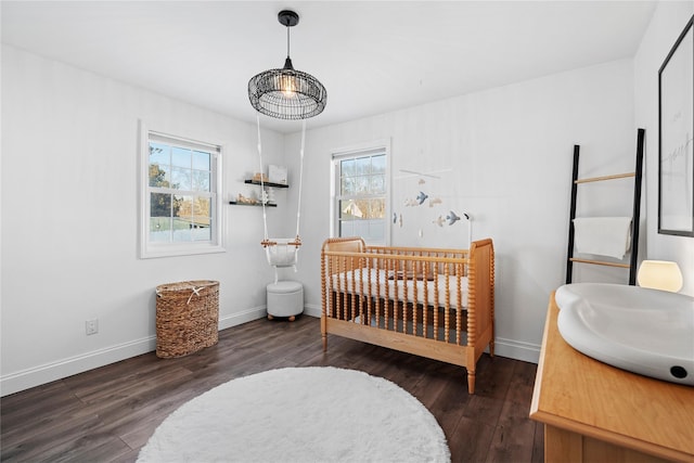 bedroom with multiple windows, dark hardwood / wood-style flooring, and a nursery area