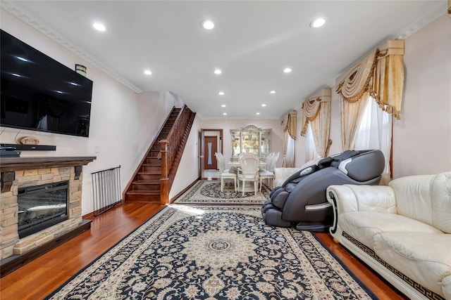 living room with crown molding, a fireplace, recessed lighting, stairway, and wood finished floors