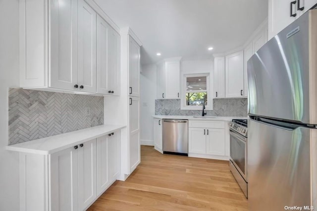 kitchen with white cabinetry, sink, light wood-type flooring, and appliances with stainless steel finishes