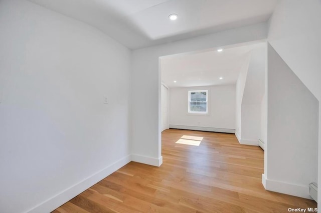 additional living space featuring a baseboard heating unit and light hardwood / wood-style flooring