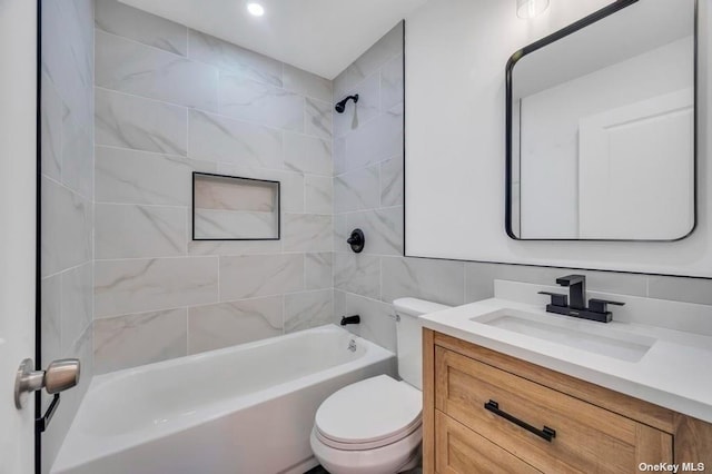 full bathroom with toilet, tasteful backsplash, tile walls, vanity, and tiled shower / bath combo