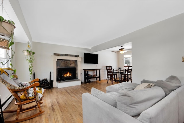 living room featuring ceiling fan, baseboard heating, and light hardwood / wood-style flooring