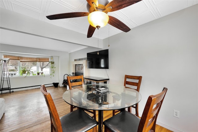 dining area featuring baseboard heating, ceiling fan, a fireplace, and light hardwood / wood-style flooring