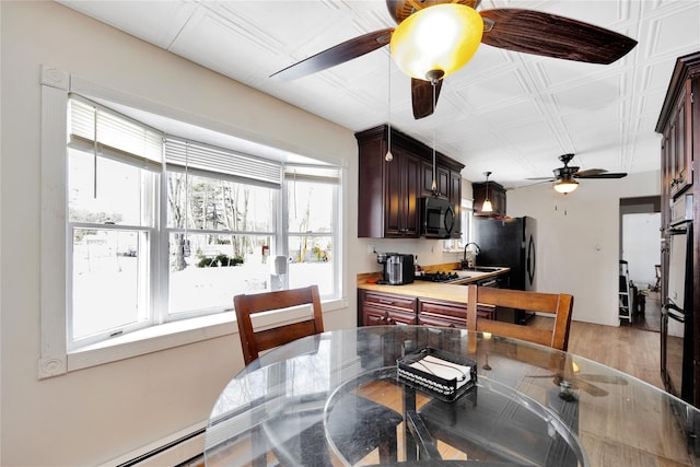 dining area featuring a baseboard radiator, wood-type flooring, sink, and ceiling fan