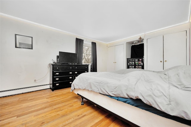 bedroom featuring wood-type flooring, a baseboard heating unit, and crown molding