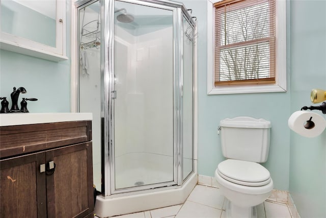 bathroom featuring tile patterned floors, toilet, a shower with shower door, and vanity