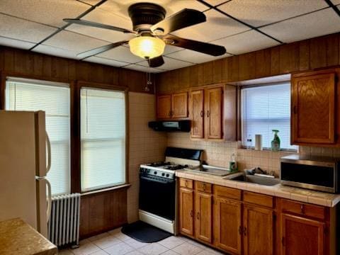 221-14 114th Rd, Cambria Heights, NY 11411 - kitchen with gas stove, radiator, stainless steel microwave, freestanding refrigerator, and exhaust hood