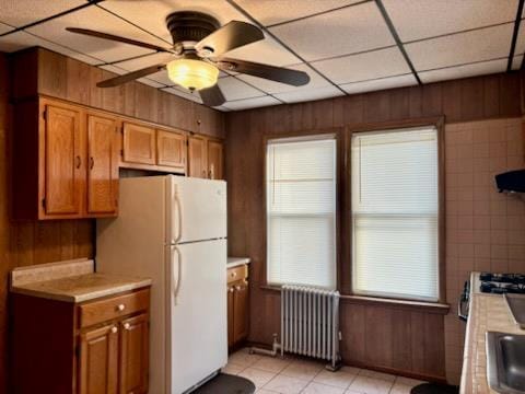 221-14 114th Rd, Cambria Heights, NY 11411 - kitchen featuring brown cabinets, a paneled ceiling, light countertops, radiator heating unit, and wood walls