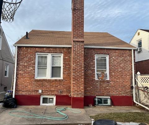 221-14 114th Rd, Cambria Heights, NY 11411 - back of house with a chimney, fence, and brick siding