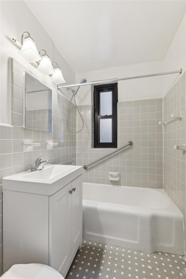 full bathroom with tile walls, vanity, tiled shower / bath, tile patterned floors, and toilet