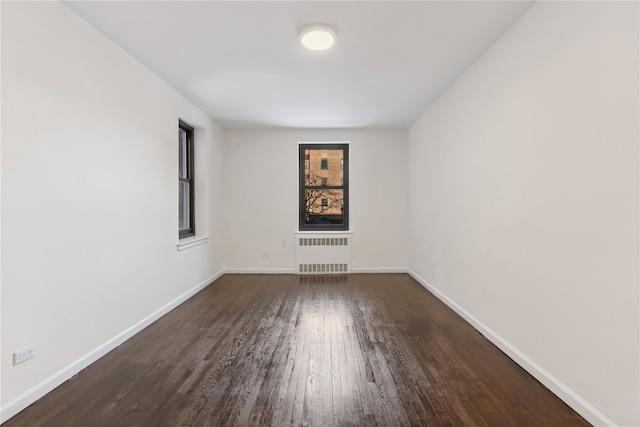 spare room with dark hardwood / wood-style flooring and radiator