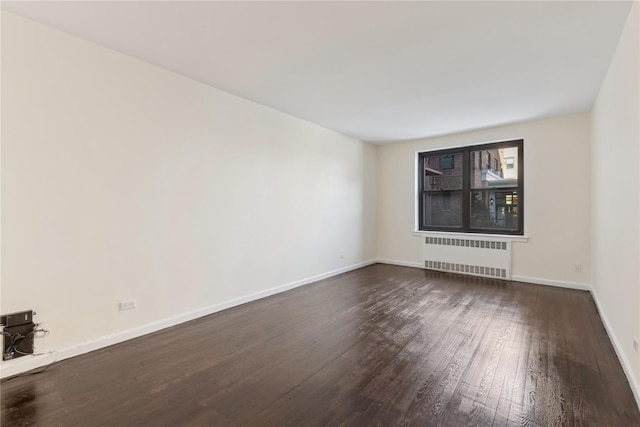 empty room featuring radiator and dark hardwood / wood-style flooring