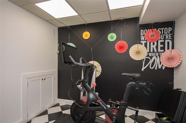 exercise room featuring light floors, baseboards, and a drop ceiling