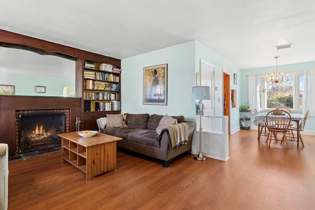 living room featuring hardwood / wood-style floors, a chandelier, and a brick fireplace